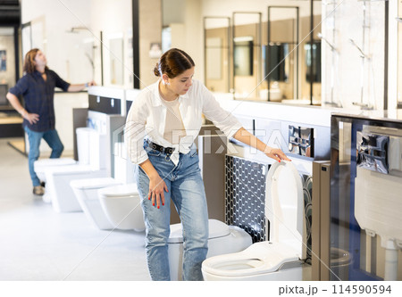 Female customer looking at white flush toilets on sale at modern store or shopping centre 114590594