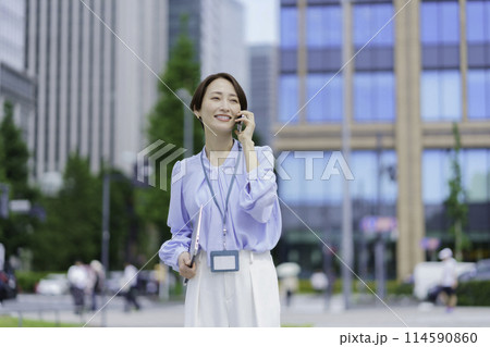 スマホで会話するオフィス街に立つビジネスウーマン スマホで会話するオフィス街に立つビジネスウーマン 114590860