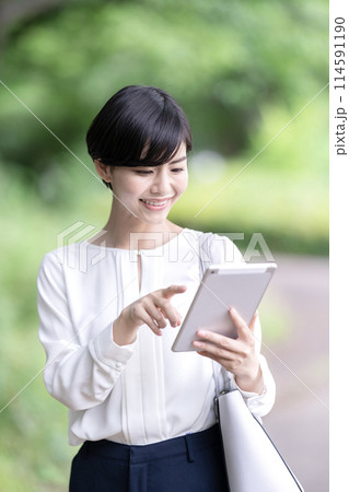 屋外でタブレットを操作するビジネスウーマン　タブレットを使う若い女性 114591190
