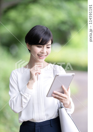 屋外でタブレットを操作するビジネスウーマン　タブレットを使う若い女性 114591191
