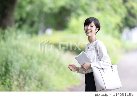 屋外でタブレットを操作するビジネスウーマン　タブレットを使う若い女性 114591199