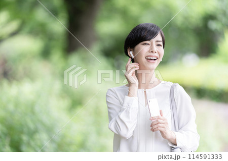 スマホで音楽を聴く若い女性　屋外 114591333