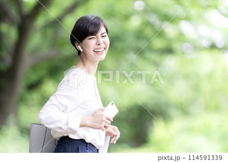 スマホで音楽を聴く若い女性　屋外 114591339