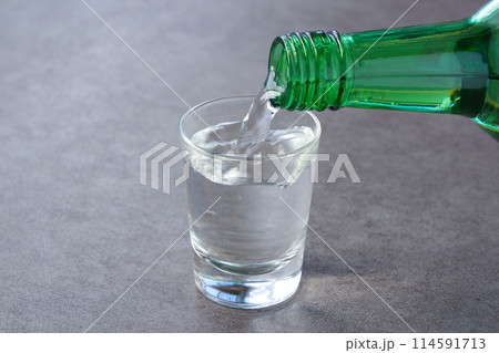 韓国の伝統的な蒸留酒、焼酎(ソジュ)をグラスに注ぐ 韓国の伝統的な蒸留酒、焼酎(ソジュ)をグラスに注ぐ 114591713