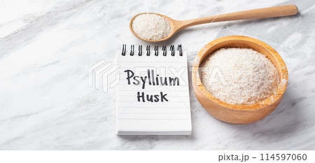 Psyllium husk in wood bowl and spoon with psyllium husk word on notebook on white marble table, copy space 114597060