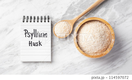 Psyllium husk in wooden bowl and spoon with psyllium husk word on notebook on marble table, top view 114597072