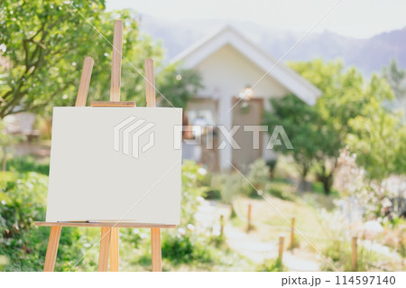 Painting canvas on wood stand outdoor with blur green nature house mountain view background 114597140