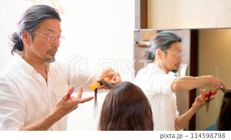 ヘアサロンにてワインディングを行うベテランの男性美容師 ヘアサロンにてワインディングを行うベテランの男性美容師 114598798