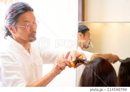 ヘアサロンにてワインディングを行うベテランの男性美容師 114598799