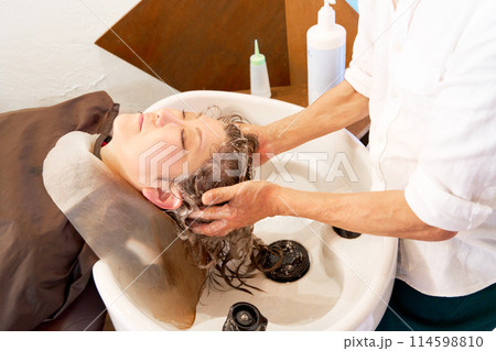 ヘアサロンにて洗髪をしてもらう女性客 ヘアサロンにて洗髪をしてもらう女性客 114598810