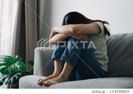 Unhappy lonely depressed woman is sitting on the couch and covering her face with her hands 114598885