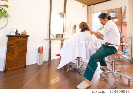ヘアサロンにて施術を行う男性美容師と女性客 ヘアサロンにて施術を行う男性美容師と女性客 114599052