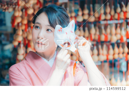 京都の土産物店で狐のお面を持つ着物姿の女性 114599512