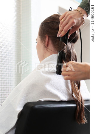 The hairdresser prepares the woman, styles her hair in the form of curls. Curling hair in the salon. Long natural hair. The concept of beauty. The hairdresser prepares the woman, styles her hair in the form of curls. Curling hair in the salon. Long natural hair. The concept of beauty. 114600161