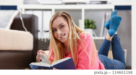 young beautiful blond woman lie on the floor read book 114601198