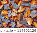 close-up image of a pile of chopped firewood. warm tones and visible grain and rings indicate the wood is ready for use as fuel. 114602126