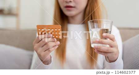 Woman holding birth control pills and a glass of water at home. Concept of health, contraception, and women's healthcare 114602377