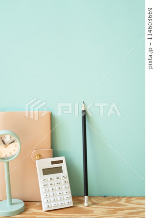 Workspace diary note, calculator, pencil, clock on wooden desk. mint wall background Workspace diary note, calculator, pencil, clock on wooden desk. mint wall background 114603669