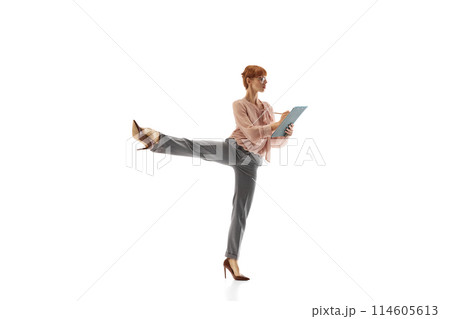 Focused and concentrated woman, employee in formal wear making notes in documents, standing in dynamic pose isolated on white background Focused and concentrated woman, employee in formal wear making notes in documents, standing in dynamic pose isolated on white background 114605613