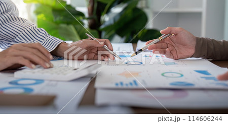 Business professionals analyzing financial charts in a modern office. Concept of teamwork, strategy, and data analysis 114606244