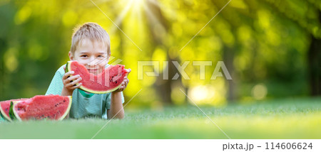 Cute child lying on the grass and eating juicy slice of watermelon. Cute child lying on the grass and eating juicy slice of watermelon. 114606624