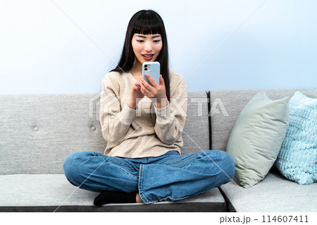 ソファでスマホを触る若い女性 114607411