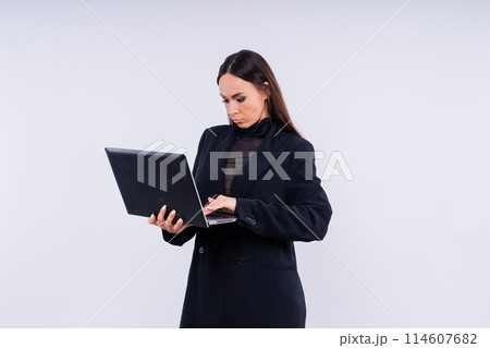 Attractive woman wearing business suit with computer angry facial expression holding a hammer 114607682