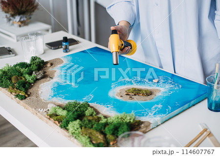 Artist Perfecting Epoxy Resin Coastal Scene with hand burner Artist Perfecting Epoxy Resin Coastal Scene with hand burner 114607767