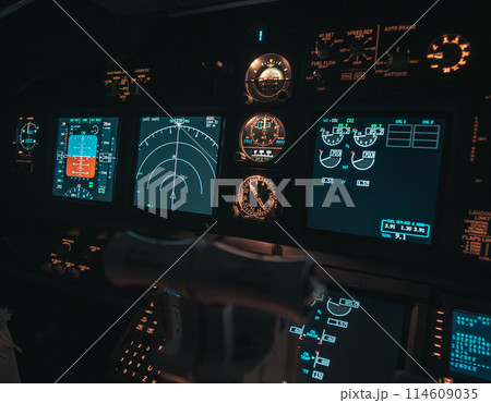 Cockpit view of an airplane during a night-time flight with illuminated instrument panels 114609035
