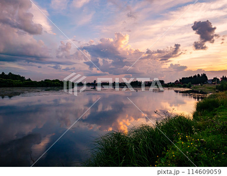 Calm river at sunset with reflective sky in rural countryside landscape 114609059