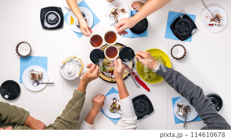people clanging cups with tea together at the table with dessert people clanging cups with tea together at the table with dessert 114610678