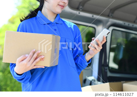 荷物を持ちスマホを見る配送ドライバー女性 荷物を持ちスマホを見る配送ドライバー女性 114611027