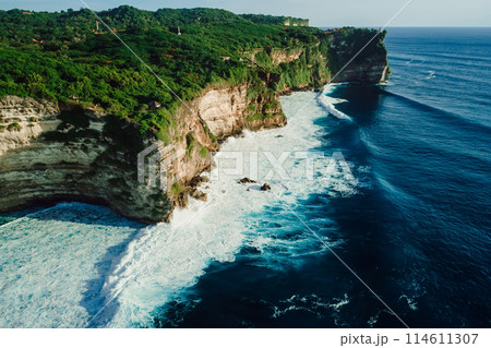 Rocky cliff coastline and ocean with waves near Uluwatu temple in Bali 114611307