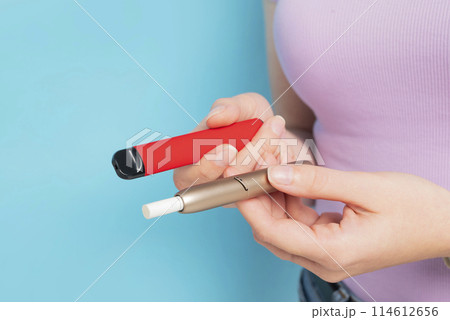 Disposable electronic cigarette and iqos in hand close up. Disposable electronic cigarette and iqos in hand close up. 114612656