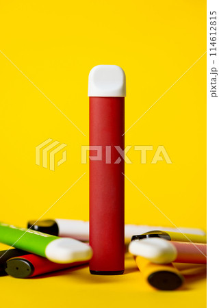Colorful disposable electronic cigarettes on a yellow background. The concept of modern smoking, vaping and nicotine. 114612815