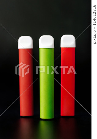 Colorful disposable electronic cigarettes on a black background. The concept of modern smoking, vaping and nicotine. Colorful disposable electronic cigarettes on a black background. The concept of modern smoking, vaping and nicotine. 114612816