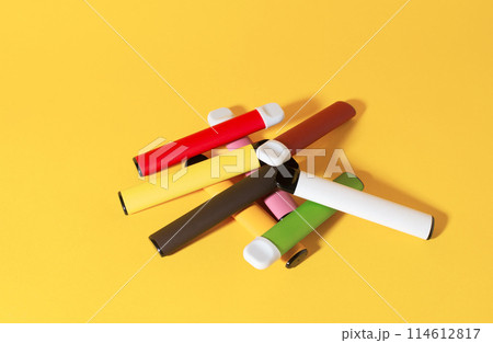 Layout of colorful disposable electronic cigarettes with shadows on a yellow background. The concept of modern smoking, vaping and nicotine. Top view 114612817