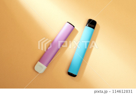 disposable electronic cigarettes with shadow on a beige background with copy space. The concept of modern smoking, vaping and nicotine. disposable electronic cigarettes with shadow on a beige background with copy space. The concept of modern smoking, vaping and nicotine. 114612831