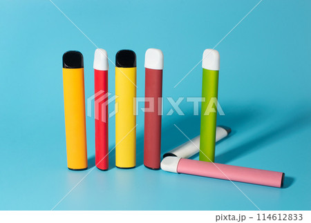 Set of colorful disposable electronic cigarettes with shadows on a blue background. The concept of modern smoking, vaping and nicotine. Top view 114612833