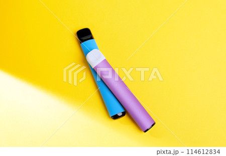 disposable electronic cigarettes with shadow on a yellow background with copy space. The concept of modern smoking, vaping and nicotine. top view. 114612834