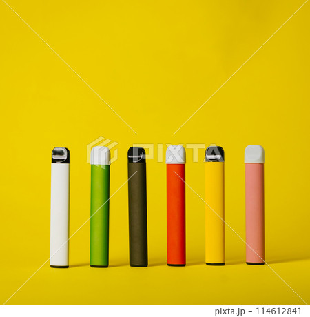 Set of colorful disposable electronic cigarettes with shadows on a yellow background. The concept of modern smoking, vaping and nicotine Set of colorful disposable electronic cigarettes with shadows on a yellow background. The concept of modern smoking, vaping and nicotine 114612841