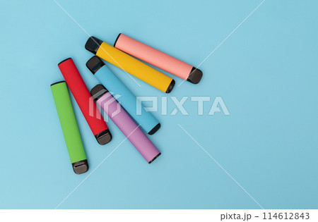 Set of colorful disposable electronic cigarettes on a blue background. The concept of modern smoking. Top view 114612843