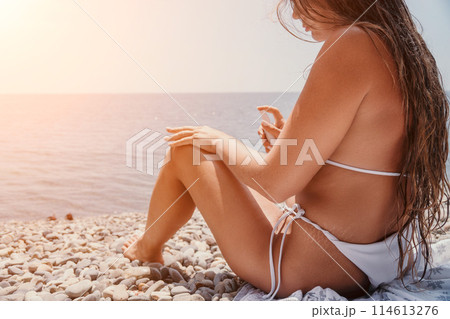 Woman sunscreen sea. Happy lady applies sunblock cream on tanned skin before sunbathing. Female On Sea Vacation Holiday Resort. Woman Use Suncare Lotion On Beach, Applying Sunscreen Lotion On Body 114613276