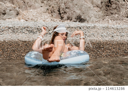 Woman summer sea. Happy woman swimming with inflatable donut on the beach in summer sunny day, surrounded by volcanic mountains. Summer vacation concept. 114613286