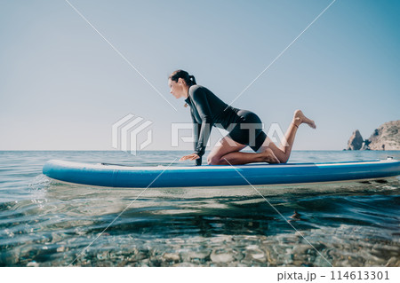 Woman sup yoga. Happy sporty woman practising yoga pilates on paddle sup surfboard. Female stretching doing workout on sea water. Modern individual female hipster outdoor summer sport activity. Woman sup yoga. Happy sporty woman practising yoga pilates on paddle sup surfboard. Female stretching doing workout on sea water. Modern individual female hipster outdoor summer sport activity. 114613301