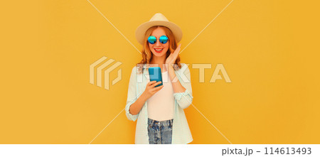 Summer portrait happy surprised young woman with mobile phone looking at device on yellow background 114613493