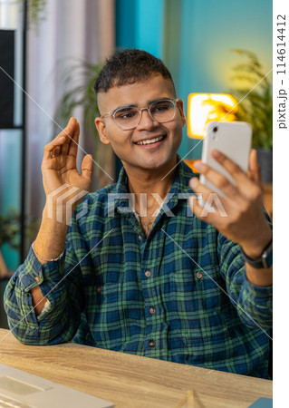Happy Indian man taking selfie on smartphone communicating video call home online with subscribers 114614412
