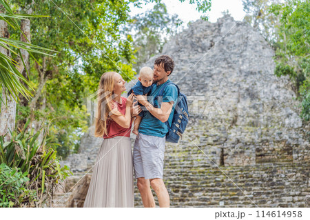 Mom, dad and baby tourists at Coba, Mexico. Ancient mayan city in Mexico. Coba is an archaeological area and a famous landmark of Yucatan Peninsula. Cloudy sky over a pyramid in Mexico 114614958