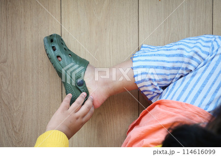 little girl feet trying to remove her sandal 114616099