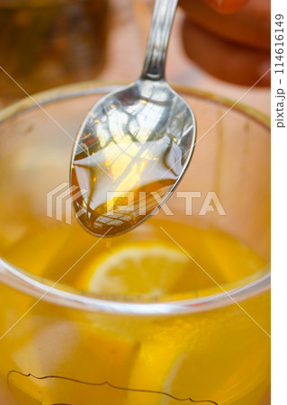 pouring honey in a cup of tea pouring honey in a cup of tea 114616149